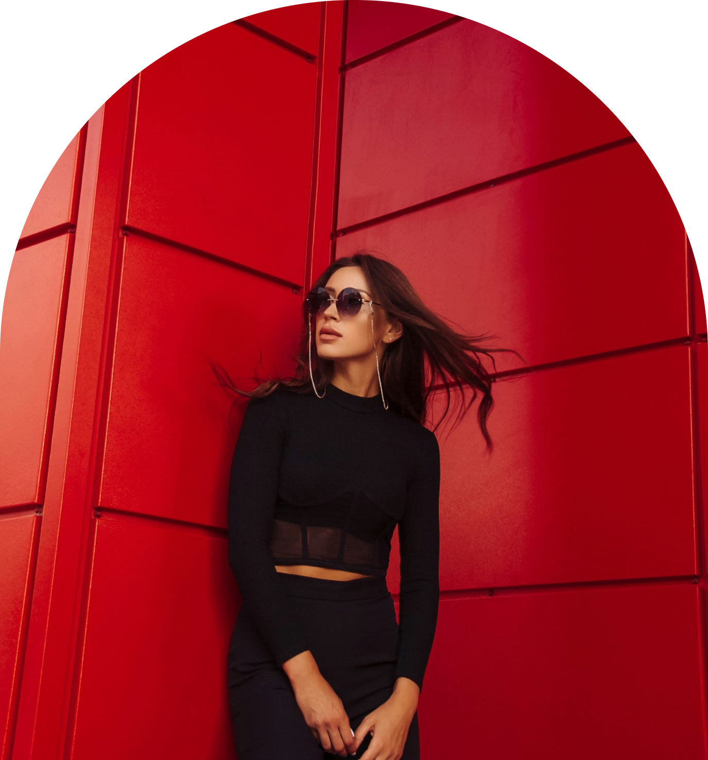 A woman in black outfit standing next to red wall.