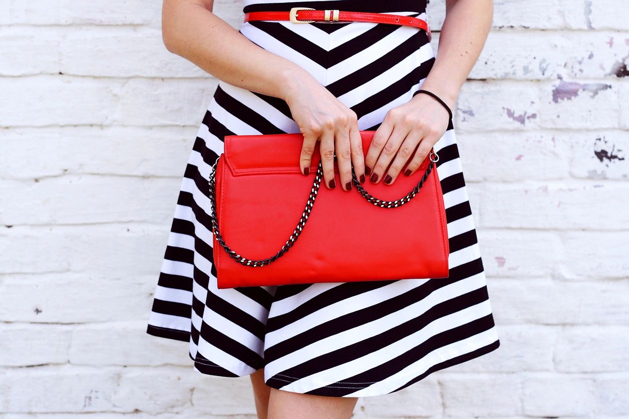 A woman holding onto a red purse in her hands.