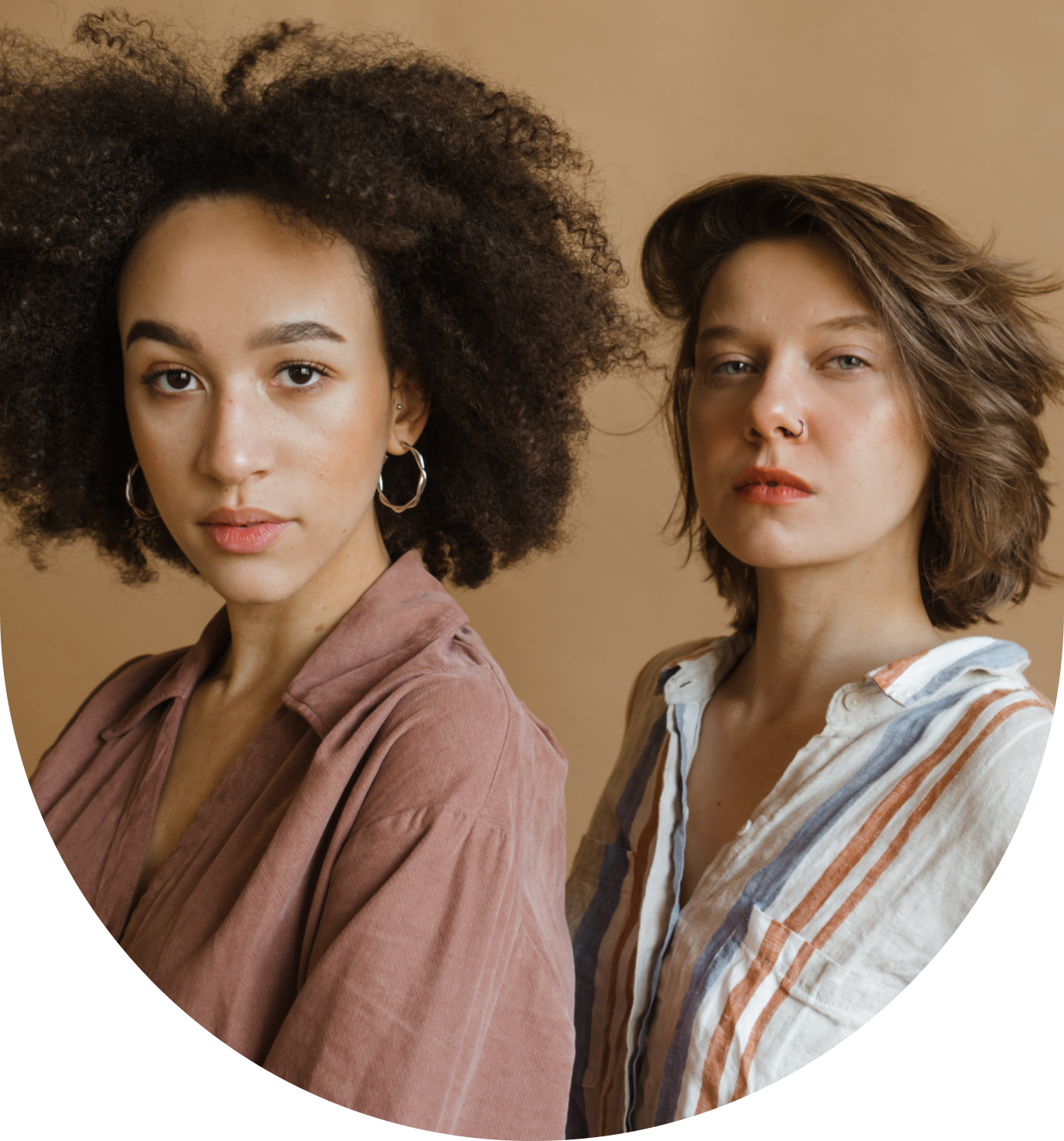 Two women standing next to each other in front of a wall.