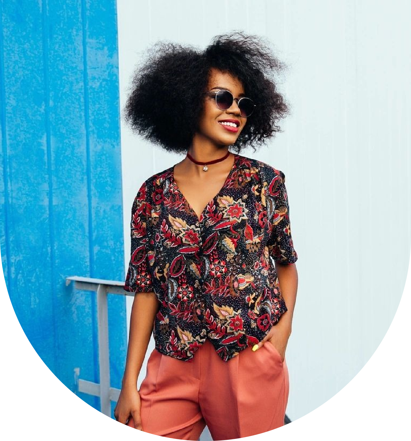 A woman with afro hair standing in front of a blue wall.